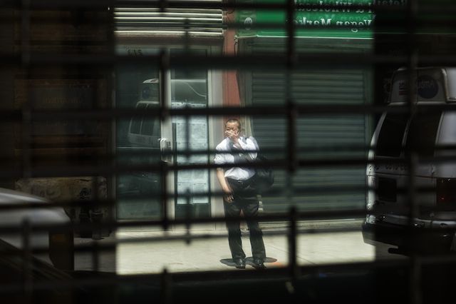 A man is reflected in the windows of a closed business in New York City in May.